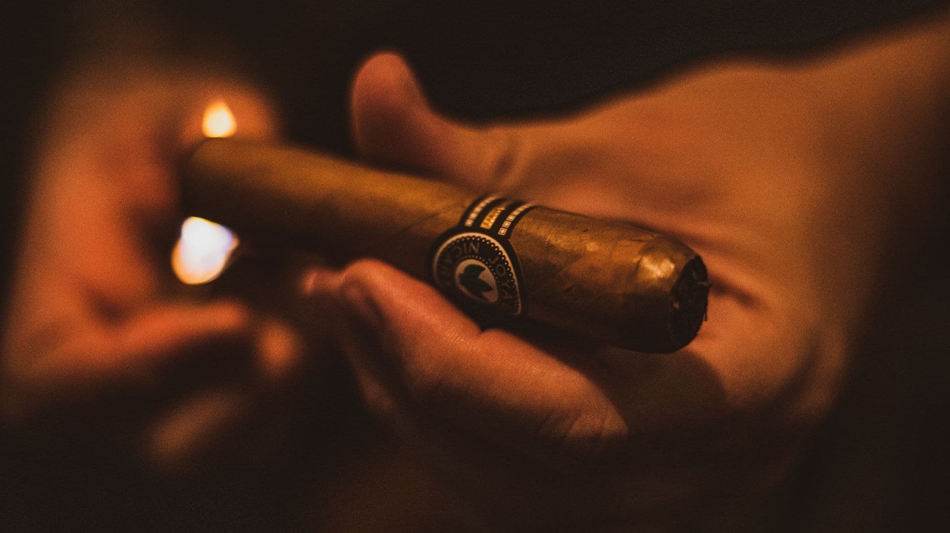 A cigar being lit in a dim lounge